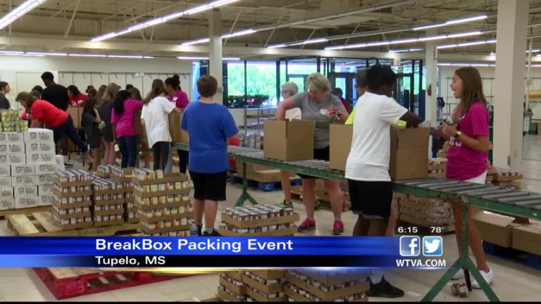 Volunteers pack boxes of food for children