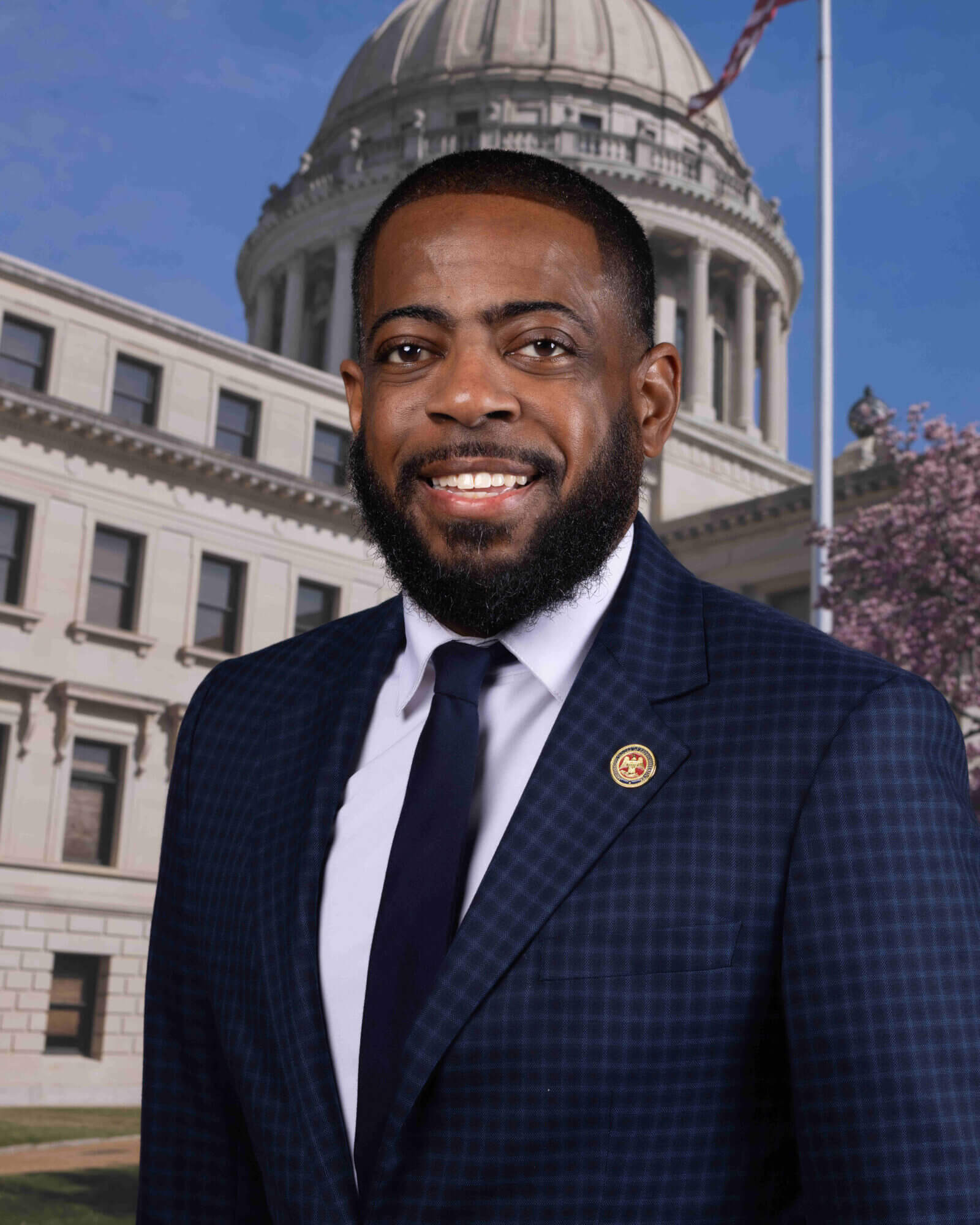 Rep. Fabian Nelson stands in front of the Mississippi State Capitol wearing a dark blue suit and tie.