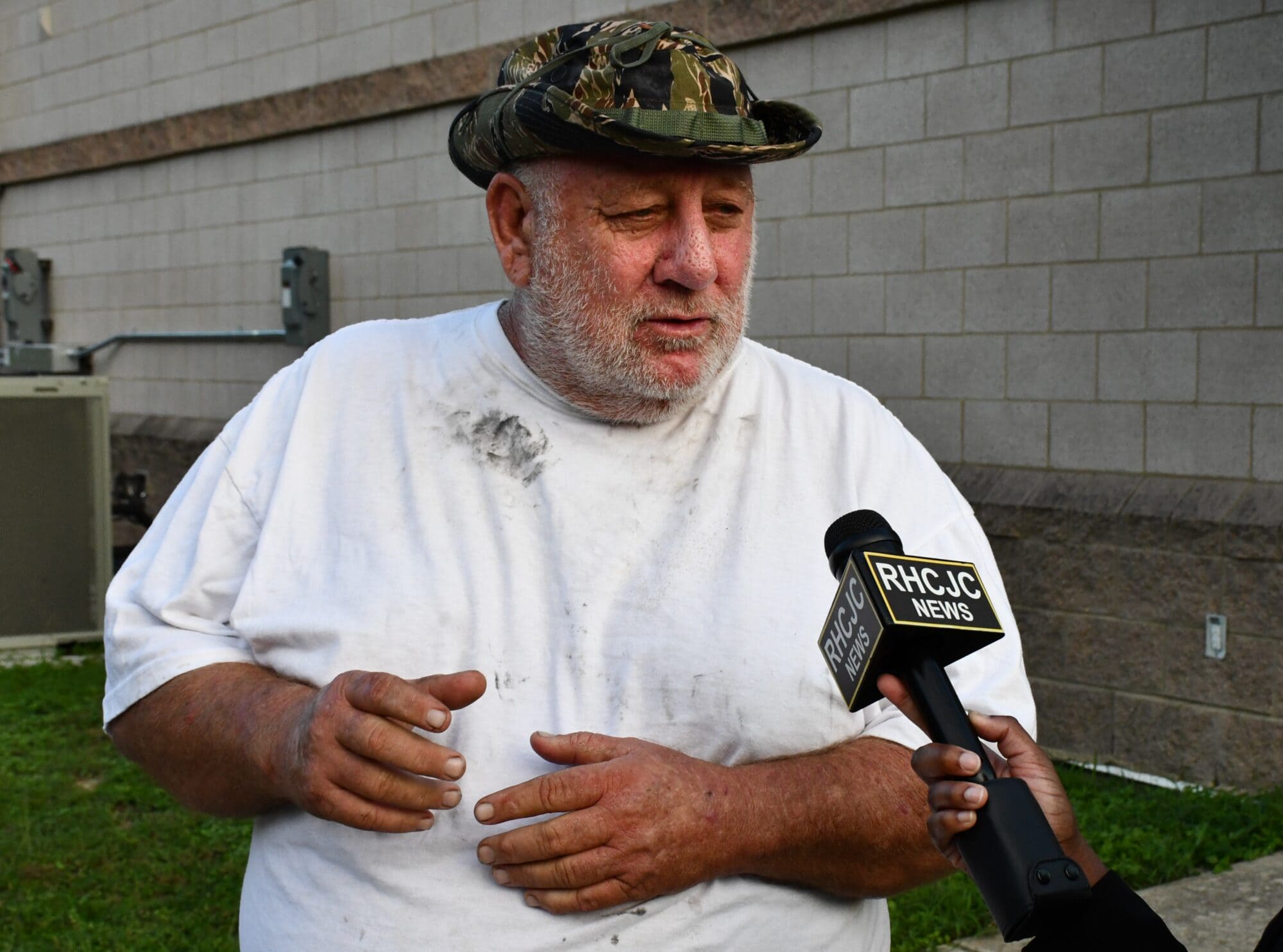 Commercial fisherman James Miller speaks into a reporter's microphone outside a building in Pass Christian, Miss.