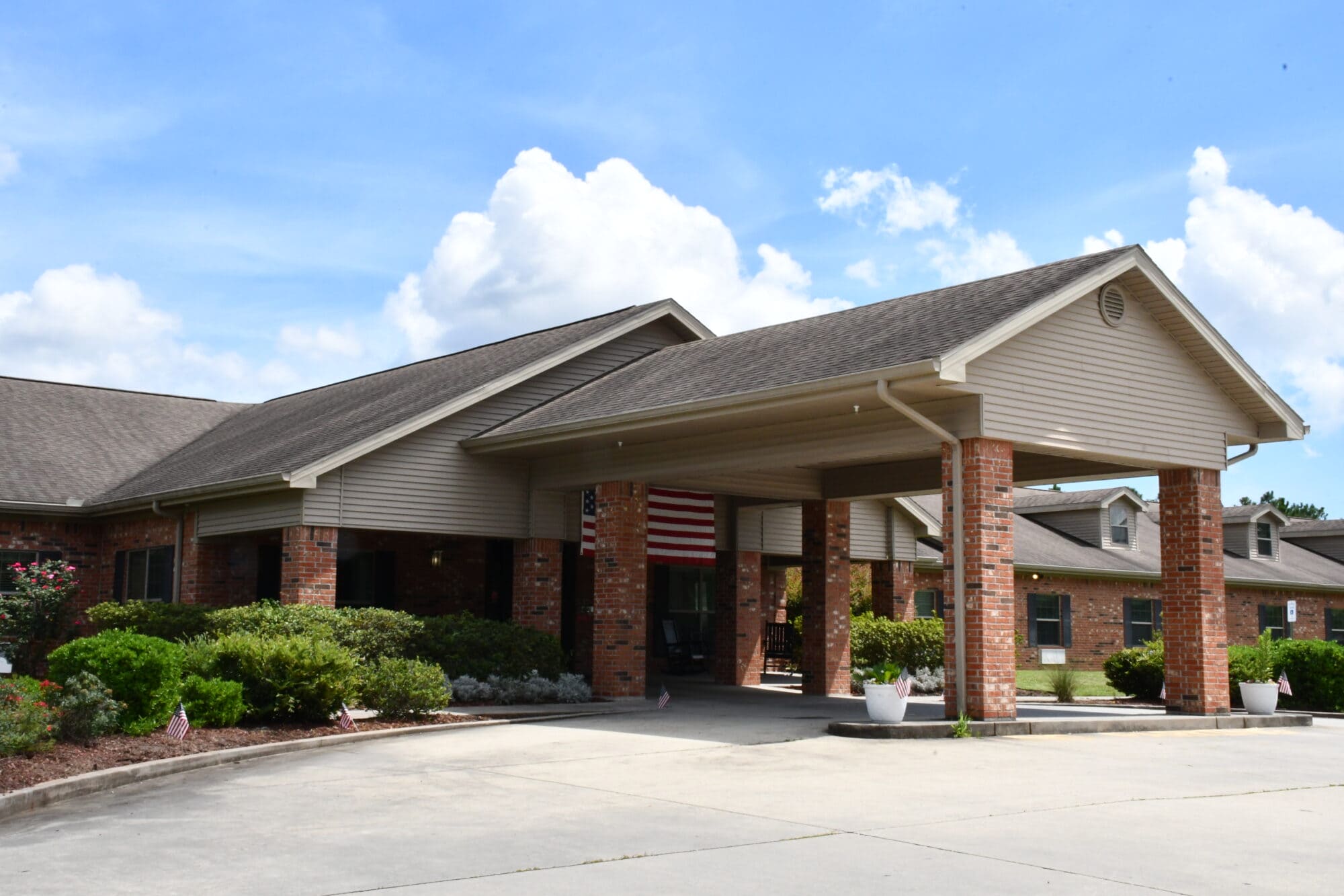 A red brick sign with black letters reads “Gulfport Care Center” and is surrounded by trees