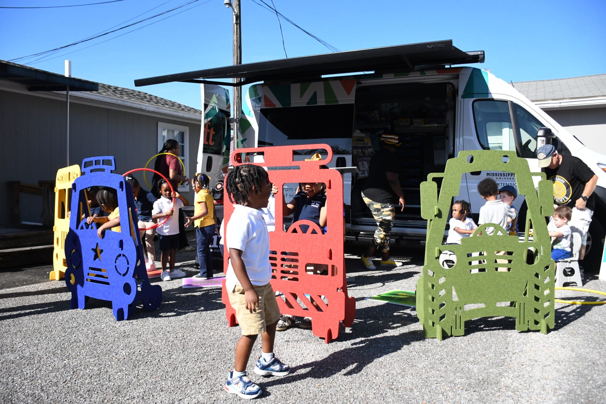 Children play with colorful activity equipment outside an MS LIFT Resource and Referral mobile unit during a Touch-a-Truck event in Pascagoula.